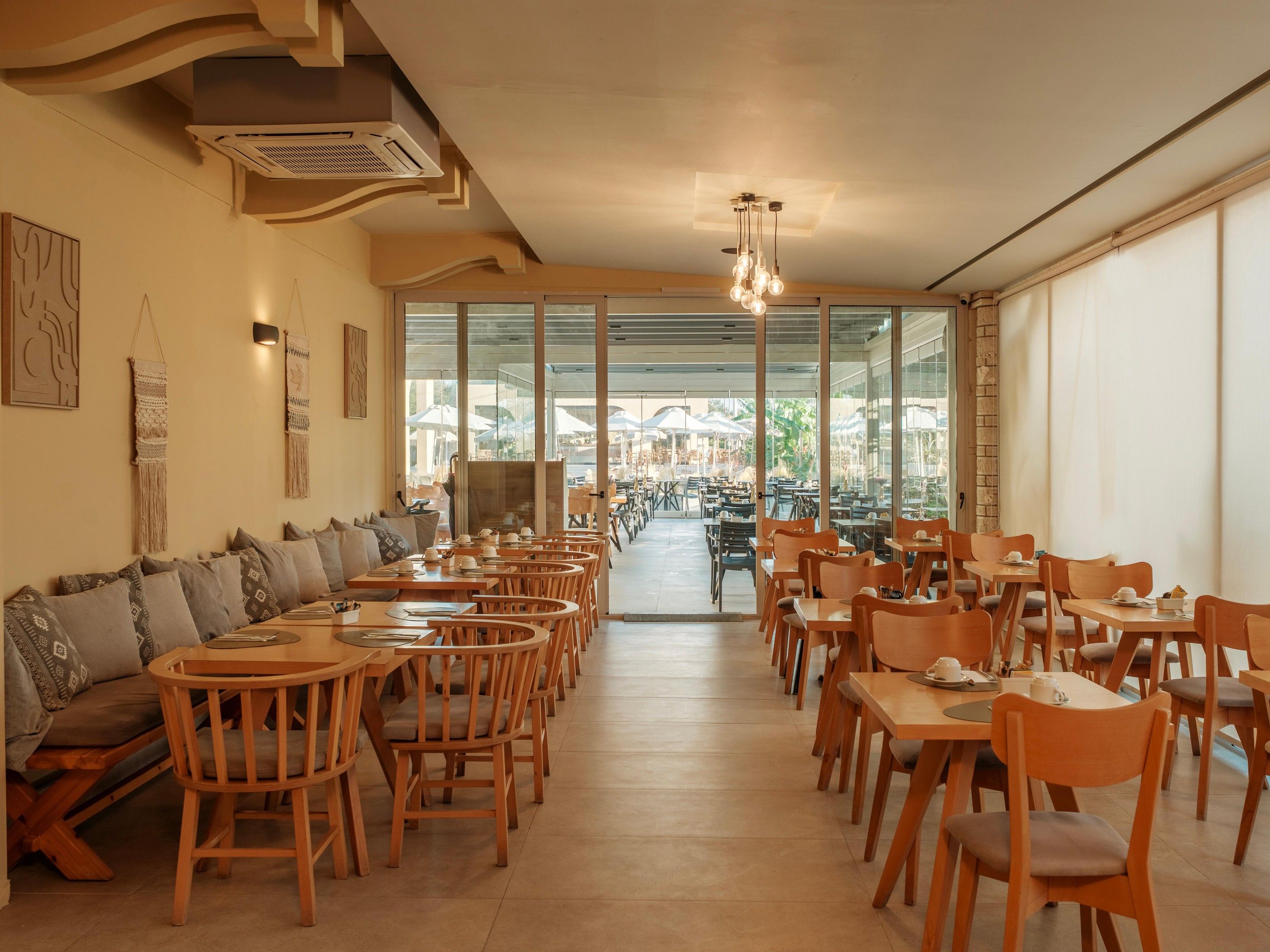 Un restaurante con mobiliario de madera, una barra larga y grandes ventanales.