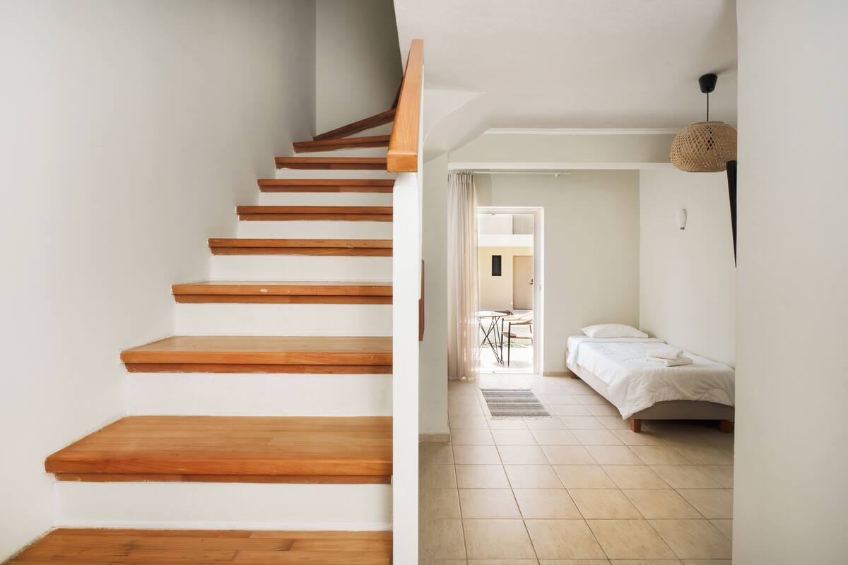 Eine Treppe mit Holzboden führt zu einem Schlafzimmer, das ein Bett und einen kleinen Tisch beinhaltet.
