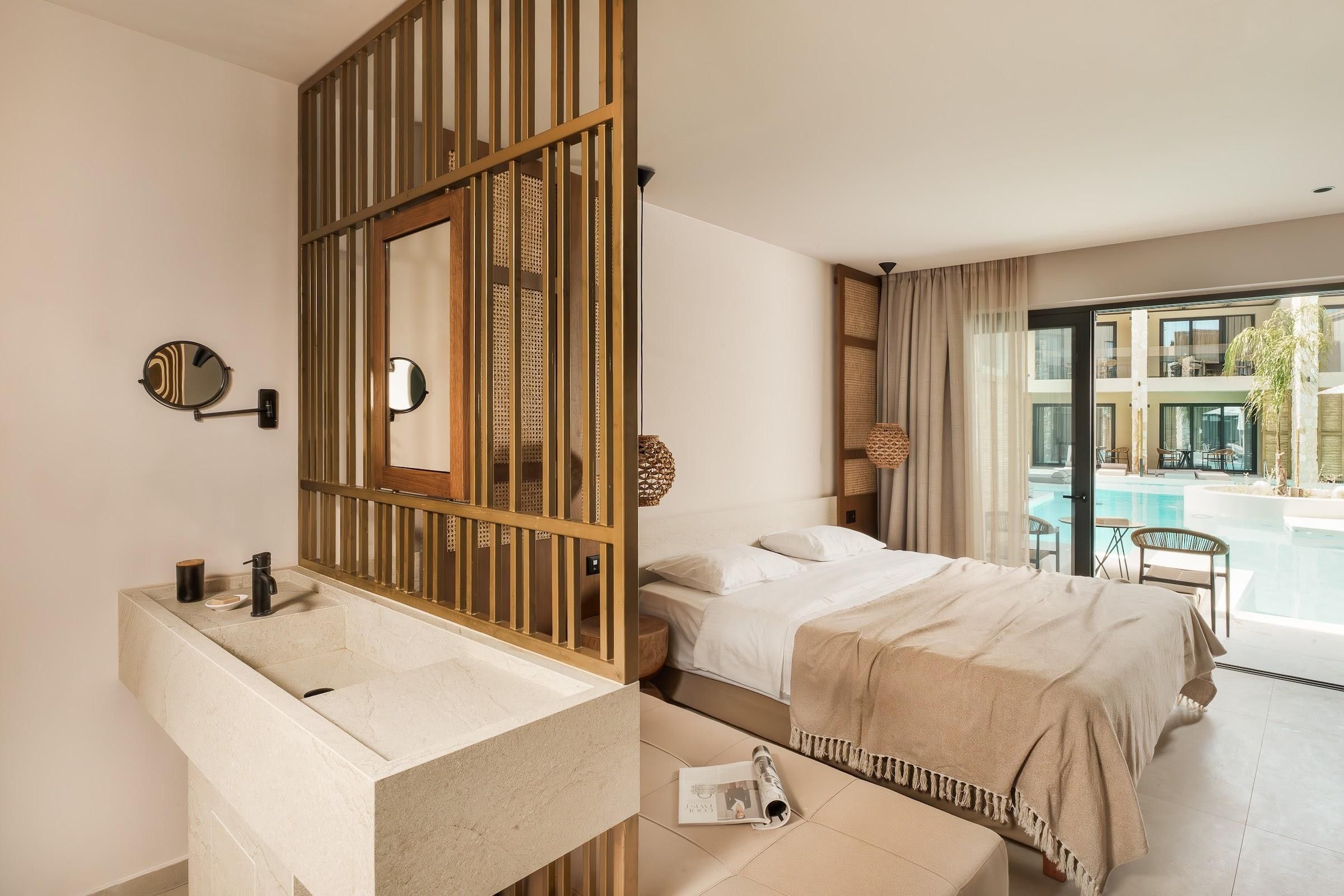 Quarto de hotel moderno com uma cama grande, banheiro com pia de mármore e vista para a piscina.