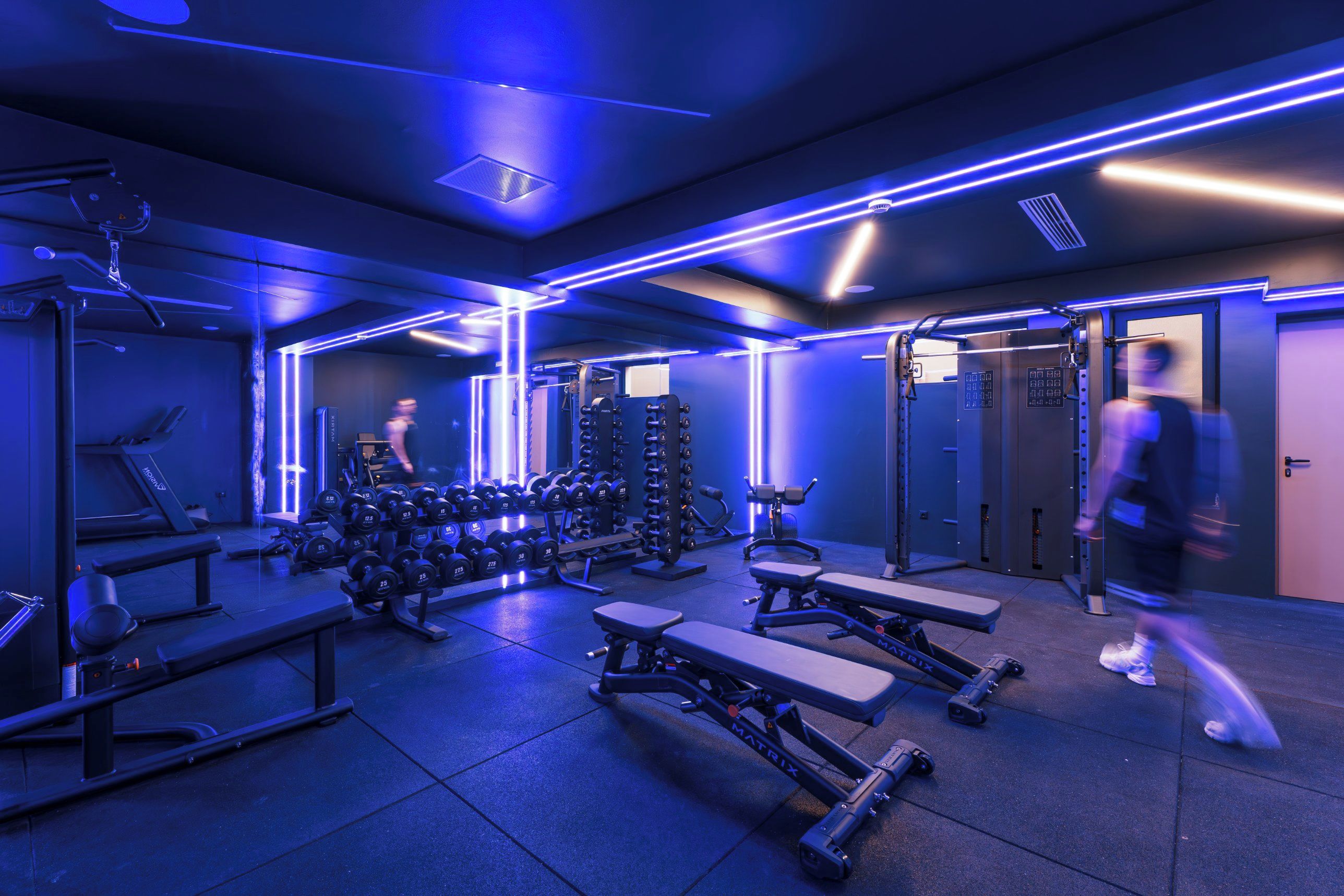 A gym with exercise equipment, treadmills, and weight racks.
