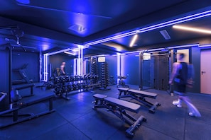 Une salle de sport équipée de machines d’exercice, de tapis de course et de supports pour les poids.