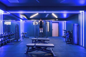 Een sportschool met gewichthefapparatuur, loopbanden en banken.