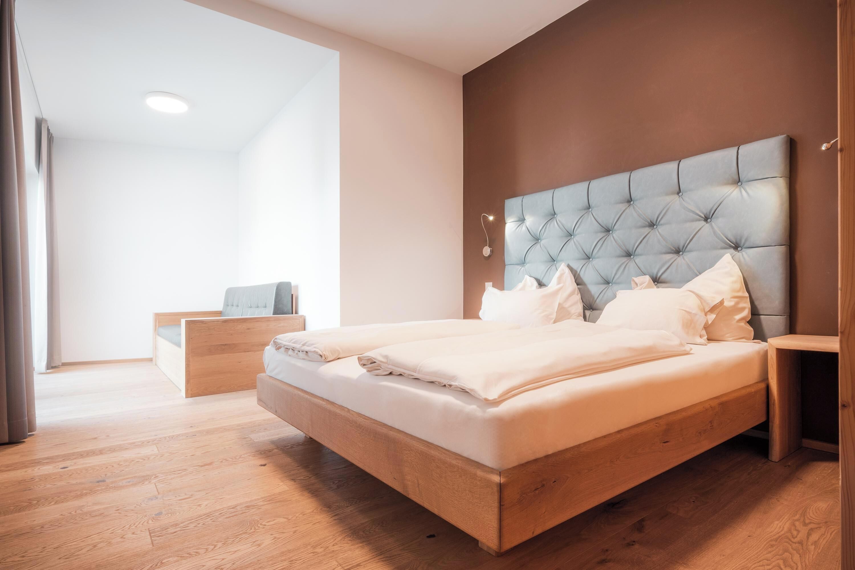 Een moderne slaapkamer met een groot bed, een houten hoofdbord en een nachtkastje.
