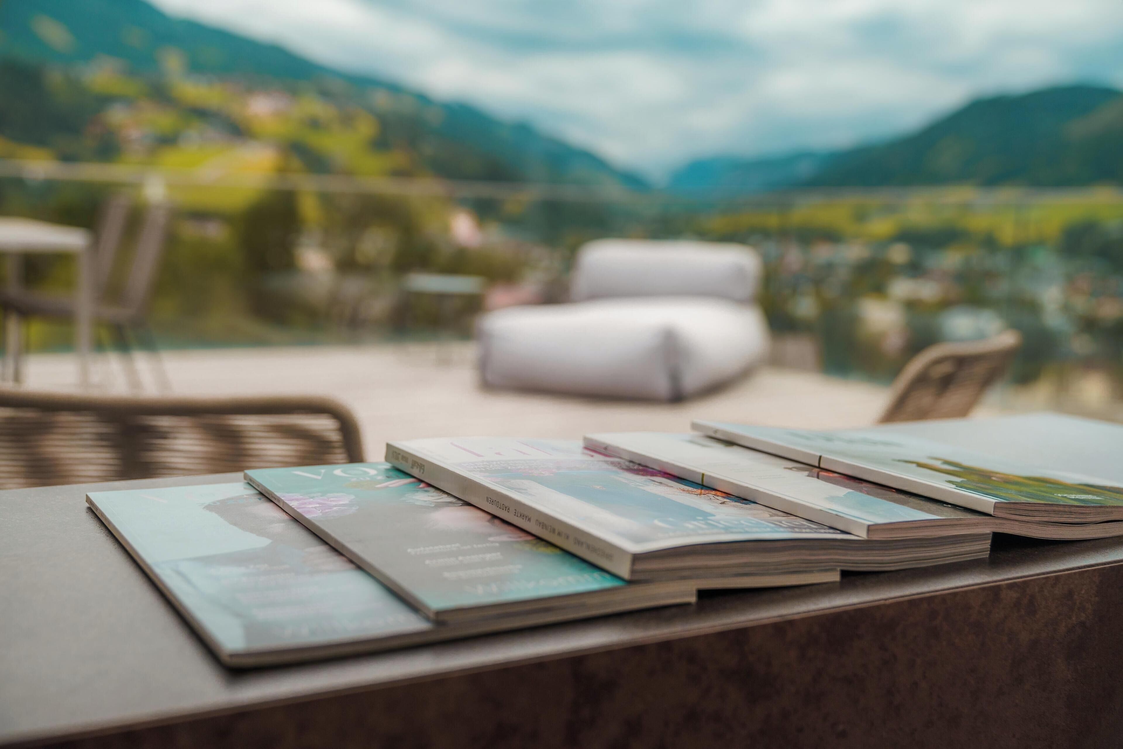 A table with magazines on it, a wicker chair, and a white sofa.