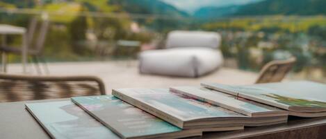 A table with magazines on it, a wicker chair, and a white sofa.