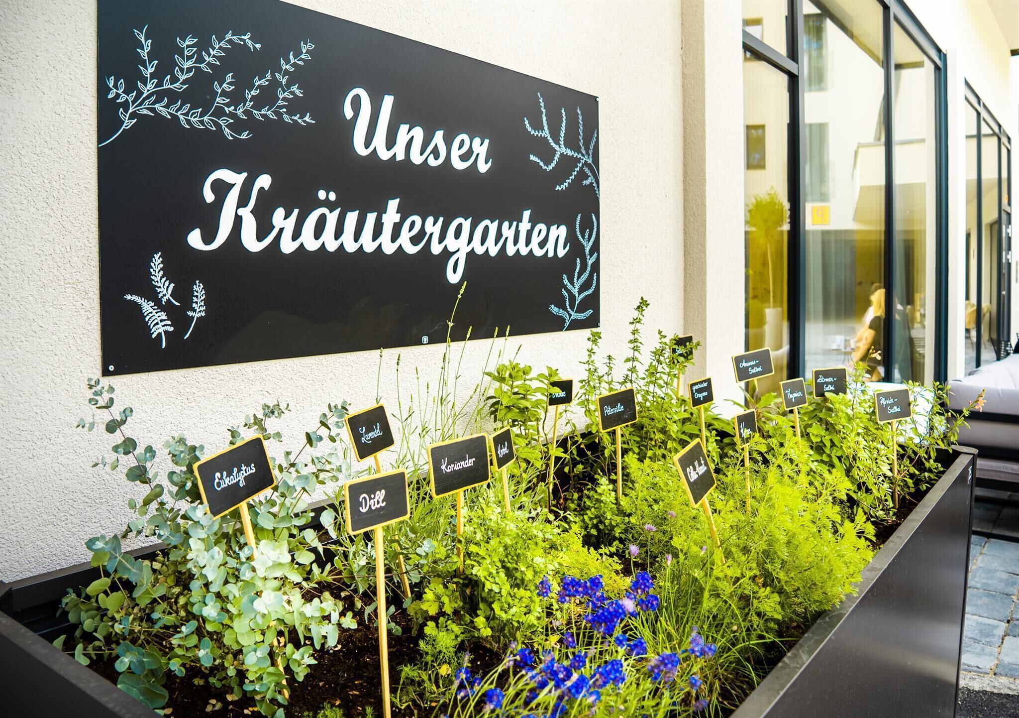 Un letrero que dice 'Unser Kräutergarten' con varias etiquetas de hierbas.