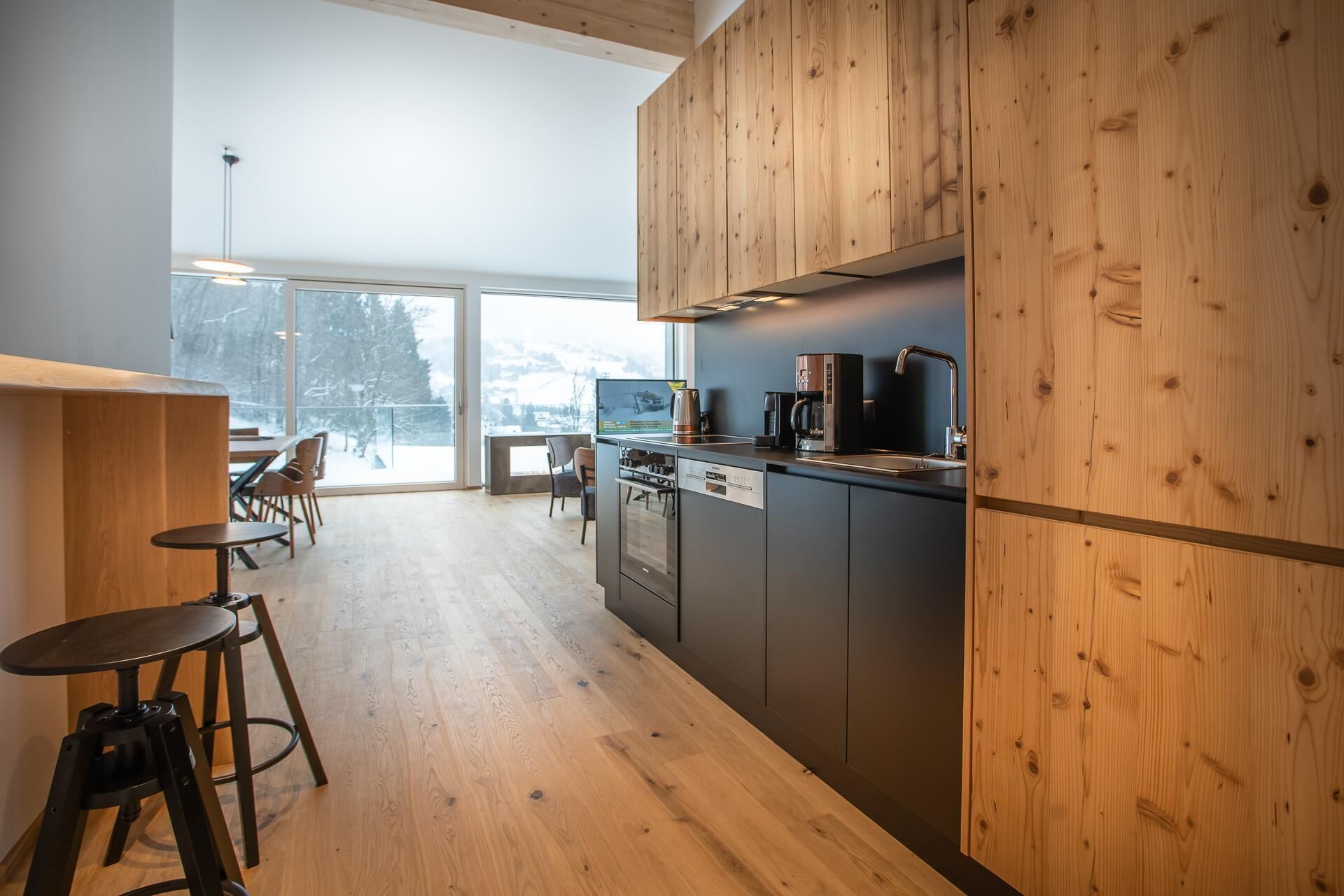 Une cuisine moderne avec des meubles en bois, un four encastré et une machine à café.