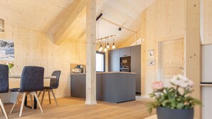Une cuisine moderne avec des murs en bois, un îlot central et des luminaires suspendus.