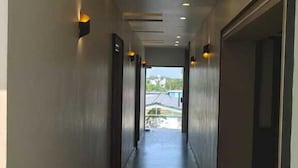 Een moderne gang met inbouwverlichting, een betegelde vloer en deuren aan beide kanten.