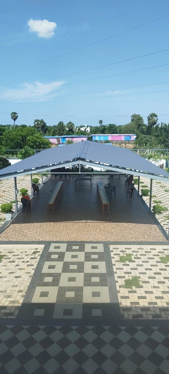 Un espace extérieur abrité, doté de tables et de chaises, entouré d’un sol à motifs et surplombé par un ciel dégagé.