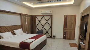 Een hotelkamer met een bed, een televisie, een bureau en een kledingkast.