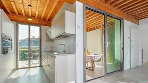 Uma cozinha moderna com teto de madeira, uma área de refeições com mesa e cadeiras, e uma porta de vidro deslizante que dá para um espaço ao ar livre.