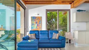 Uma sala de estar moderna com um sofá estofado azul, um tapete estampado e um grande quadro abstrato.