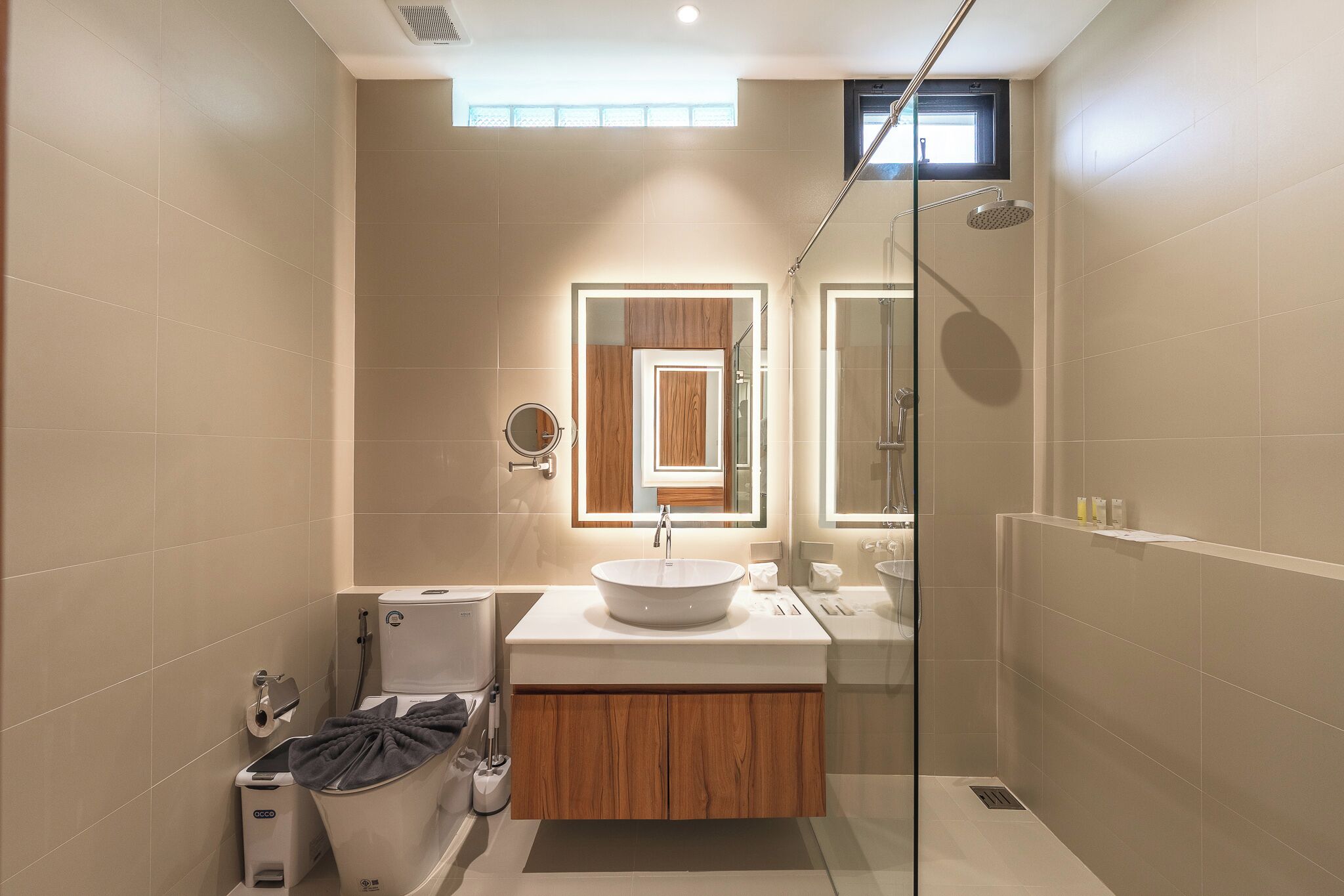 A modern bathroom with a glass shower enclosure, a built-in sink, and a vanity with a mirror.
