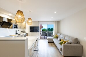 A modern kitchen with a central island, a dining area, and a living room with a sofa and a TV. - Superior Apartment: 100% Comfort (Salou)