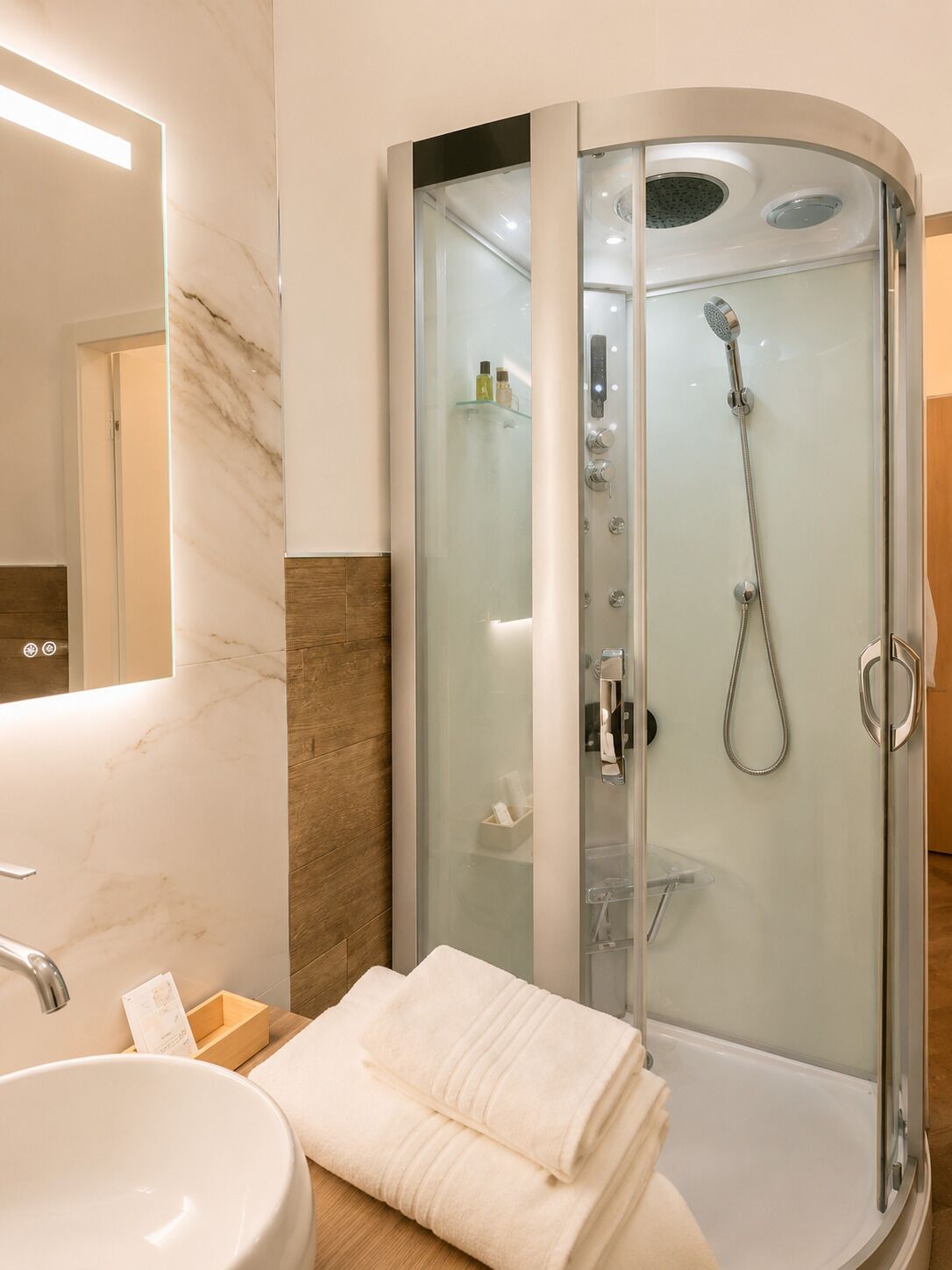 Une salle de bain moderne avec une douche à parois de verre, un lavabo et un miroir.
