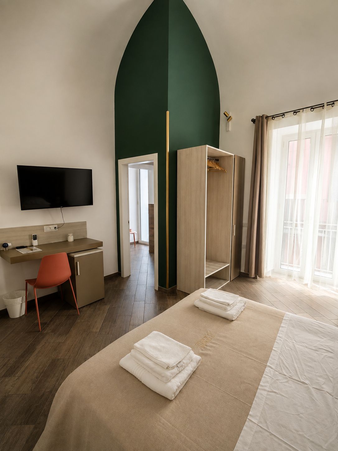 Une chambre d’hôtel avec un lit, un bureau, une télévision et une armoire.