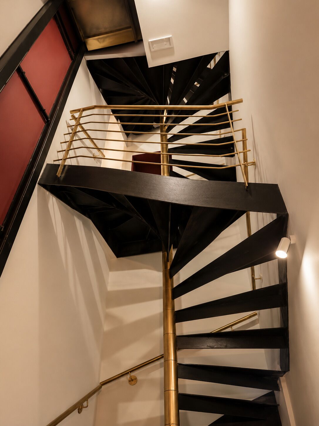 Una escalera de caracol con un vástago central y barandillas, que conduce a un nivel superior.