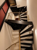 Una escalera de caracol con un vástago central y barandillas, que conduce a un nivel superior.
