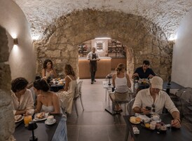 Un restaurante con paredes de piedra, una zona de bar y comensales.