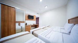 Une chambre d’hôtel avec deux lits, une armoire en bois, un bureau avec un téléviseur à écran plat et un miroir.