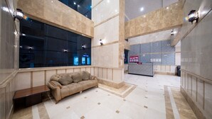 Un hall d’entrée spacieux, doté d’un canapé confortable, d’un comptoir de réception et d’une grande fenêtre donnant sur l’intérieur.
