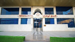 L’entrée de l’hôtel Orvana se distingue par sa façade moderne, ses grandes fenêtres en verre et son arc central.