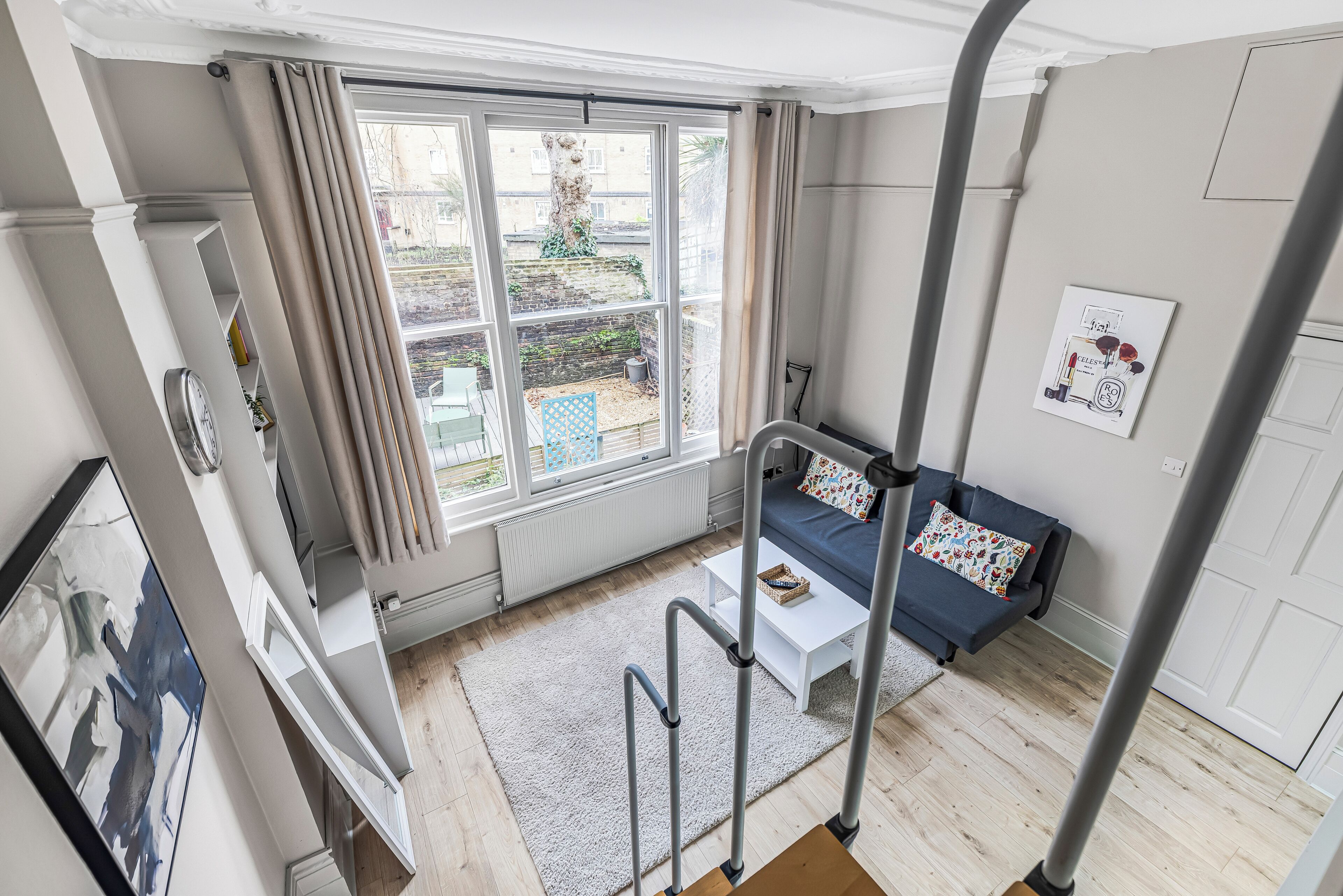 Un salon moderne avec une grande fenêtre, un canapé, une table basse et un escalier.