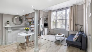 Een moderne woonkamer met een eethoek, een bank, een salontafel en een groot raam met gordijnen.