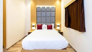 Quarto de hotel com uma cama grande, cabeceira acolchoada, luminárias de cabeceira e ventilador de teto.