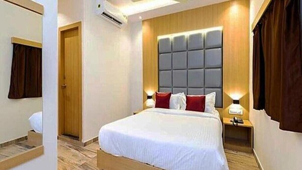 Quarto de hotel com uma cama grande, cabeceira de madeira, duas luminárias de apoio e um ventilador de teto.