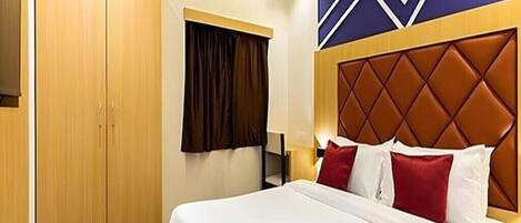 A hotel room with a large bed, a wardrobe, a window with curtains, and a decorative wall panel.