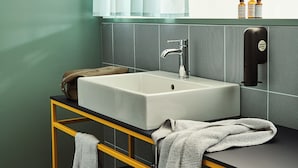 Une salle de bain moderne avec un grand lavabo, un miroir et un porte-serviettes.