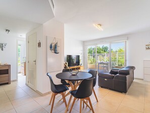 Ein modernes Wohnzimmer mit Essbereich, einer Sofagarnitur und einem Fernseher.