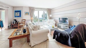 Een woonkamer met een bank, salontafel, televisie en uitzicht op de omgeving.