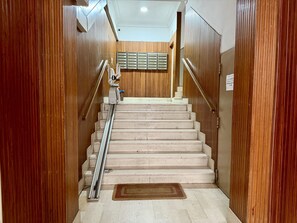Een houten interieur met een marmeren trap, een leuning en een wandgemonteerde brievenbus.