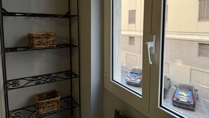 Ein Zimmer mit einer Metallregaleinheit an der Wand und einem Fenster mit Blick auf geparkte Autos.