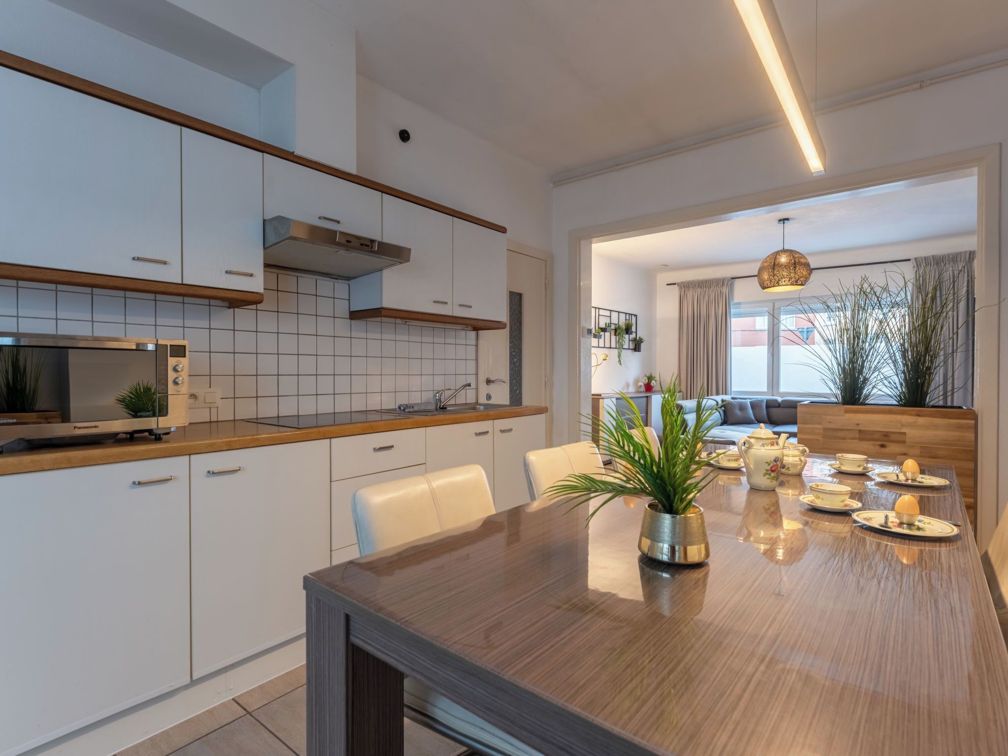 Une cuisine moderne avec des armoires blanches, un four à micro-ondes encastré et un plan de travail en bois.