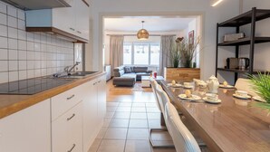 Een moderne keuken met witte kasten, een houten aanrecht en een eethoek met een tafel gedekt voor thee.