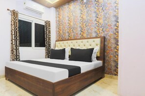 A bedroom with a bed, curtains, a window, and a floral wallpaper. - National Banaras Inn City View (Varanasi)