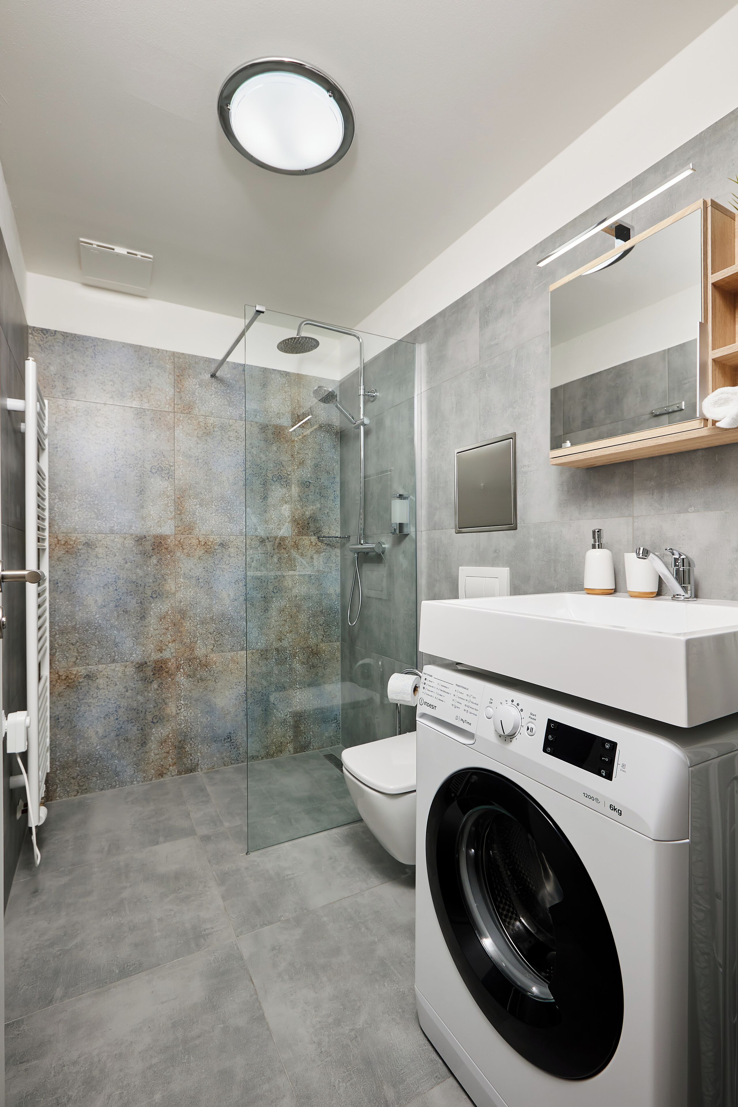 Un baño moderno con ducha de vidrio, lavadora integrada y un inodoro.