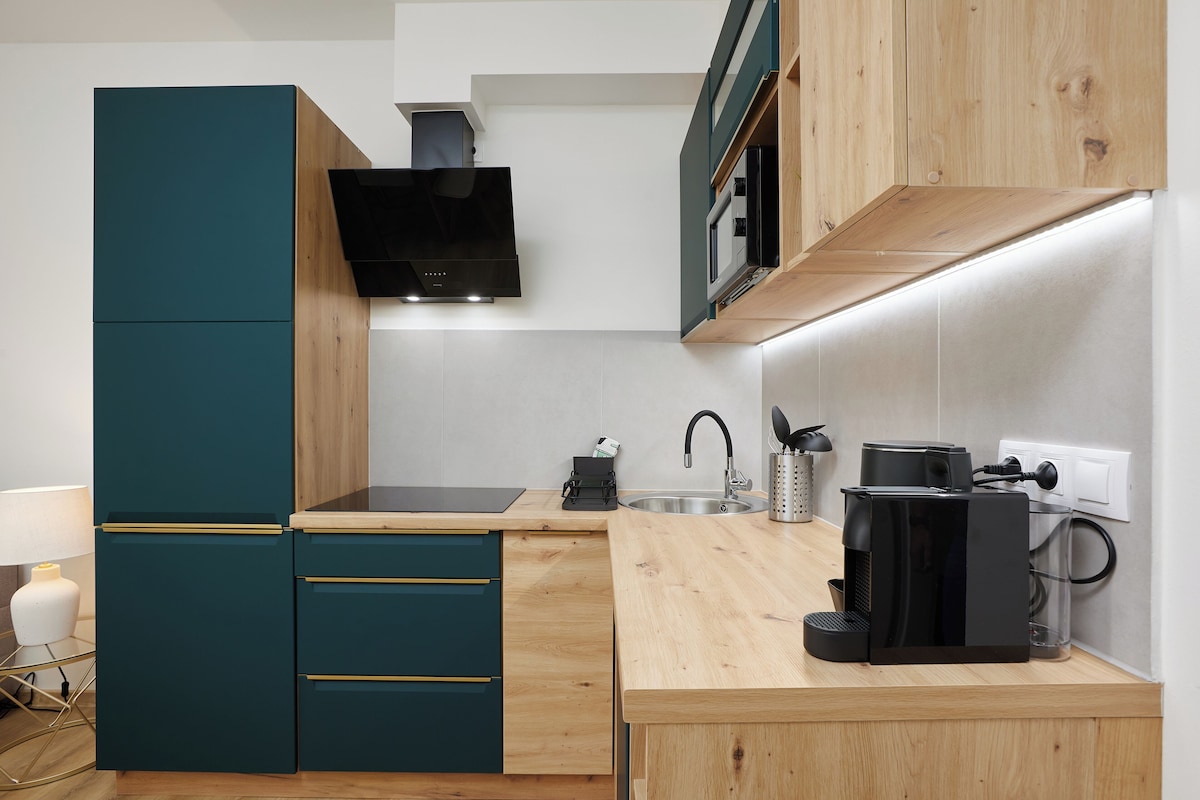 A modern kitchen with teal cabinetry, a wooden countertop, a built-in stove, and a coffee maker.