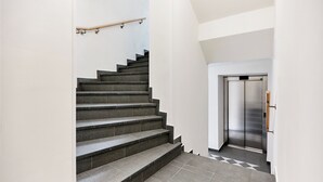 A modern staircase with a handrail, leading to an elevator. - Residence 44 (Prague)