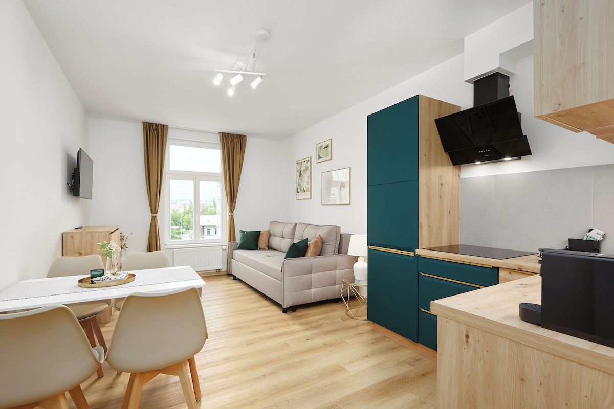 A modern kitchen with a built-in stove, a dining area with a table and chairs, and a sofa.