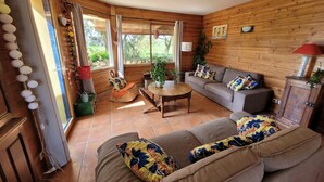 Ein gemütliches Wohnzimmer mit einer Couch, einem kleinen Tisch und einem Fenster mit Blick auf einen Garten.