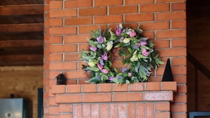 Une cheminée en briques ornée d’une guirlande et d’un vase de fleurs posé sur le manteau.