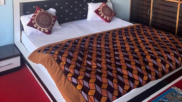 Quarto com cama, guarda-roupa e tapete vermelho.