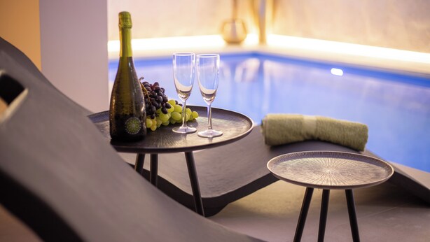 A poolside lounge with a table set with a bottle of champagne, two glasses, and grapes. - Dimore d'Elite e Spa (Monopoli)