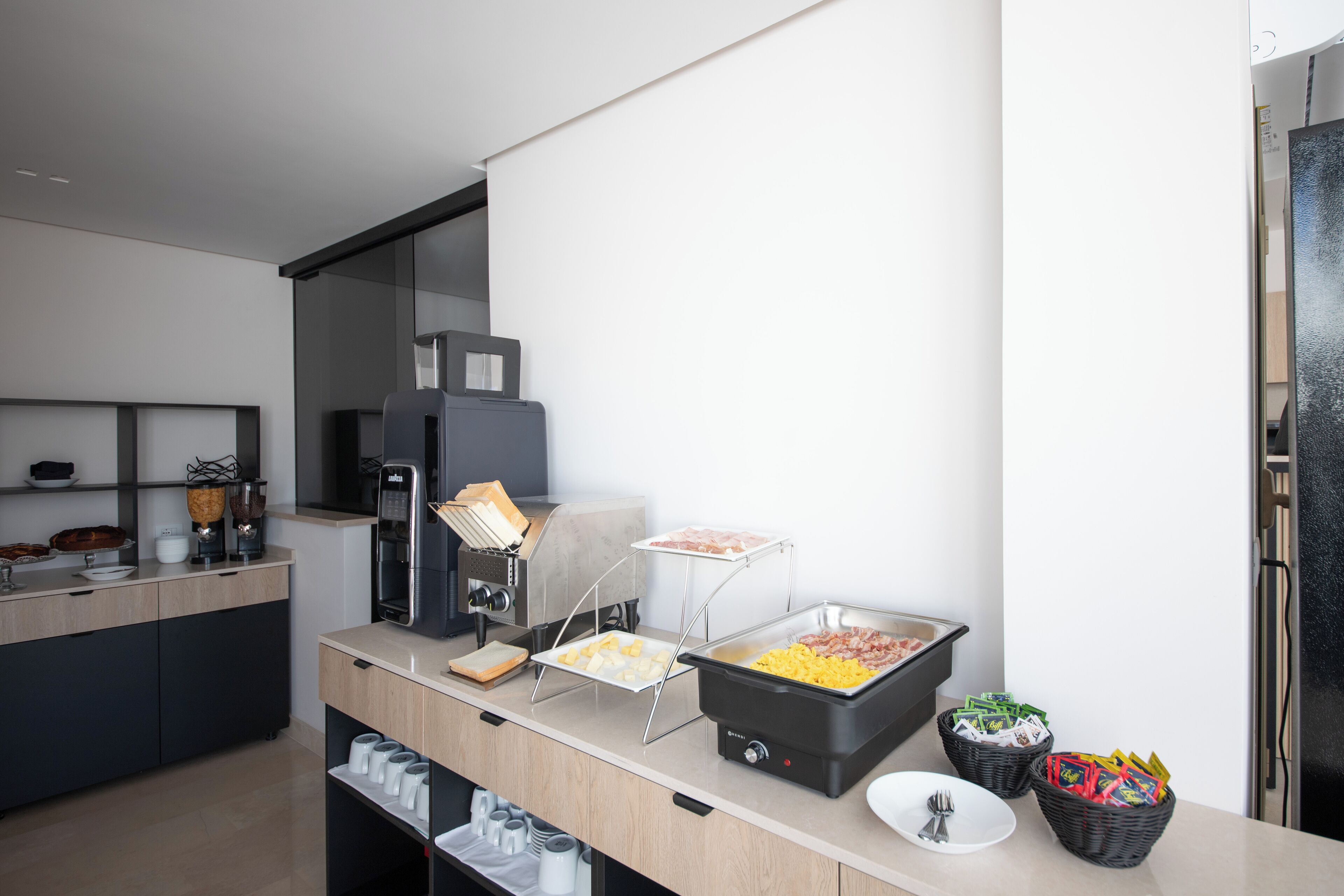 A modern kitchen with a buffet setup including a coffee machine, a toaster, and various food items.