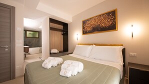 A hotel room with a bed, a bathroom, a painting, and a nightstand. - Dimore d'Elite e Spa (Monopoli)
